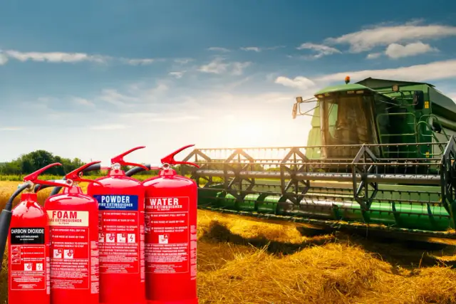 Cztery gaśnice (CO2, piankowa, proszkowa, wodna) na tle kombajnu zbożowego na polu.