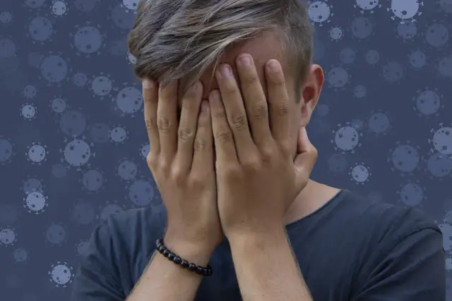 Nastolatek zakrywa twarz dłońmi na tle wirusów.
