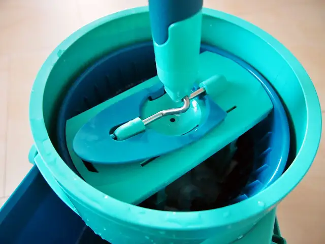 Turkusowe wiadro z obrotowym mopem i systemem odciskania.