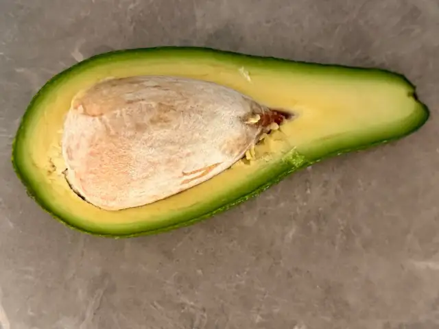 Połówka awokado z dużą pestką. Choć pestka awokado ma swoje zastosowania, istnieją przeciwwskazania do jej spożywania.