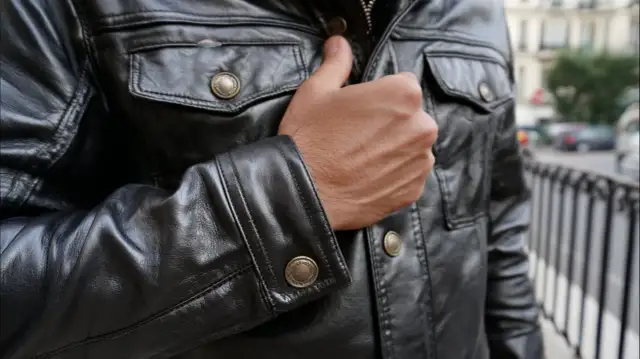 Mężczyzna w czarnej, skórzanej kurtce z ozdobnymi guzikami. Kto przerabia kurtki skórzane? Ten styl to klasyka.