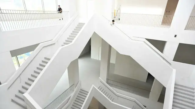 Nowoczesne, białe wnętrze muzeum z wielopoziomowymi schodami i balustradami.