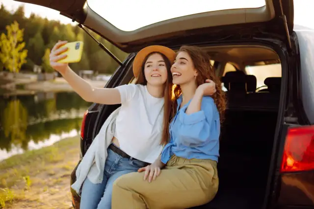 Dwie przyjaciółki robią selfie podczas babskiego wypadu nad jeziorem.