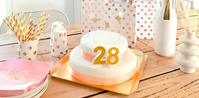 Tort urodzinowy z cyframi 28, ozdoby i prezenty na drewnianym stole.