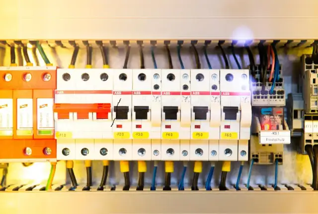 Wnętrze rozdzielni elektrycznej z widocznymi zabezpieczeniami, przewodami i elementami sterującymi.