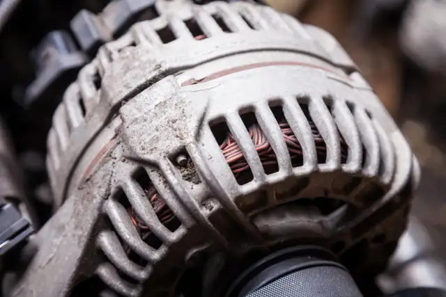 Zbliżenie na zużyty alternator samochodowy z widocznymi uzwojeniami.