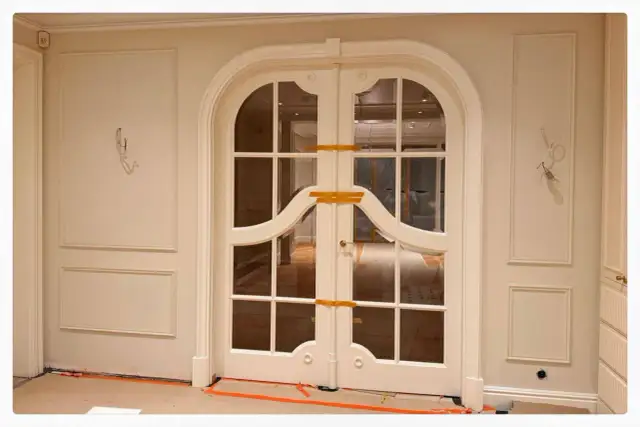 Eleganckie drzwi dwuskrzydłowe z łukiem i panelami ściennymi. Planowanie sztukaterii w tym wnętrzu doda mu klasy.