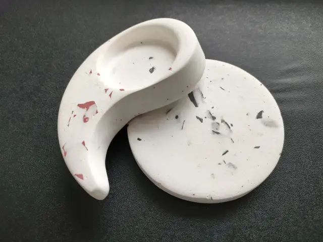 Gips polimerowy gdzie kupić? Dwa ozdobne elementy z gipsu polimerowego, jeden w kształcie półksiężyca, drugi okrągły, z czarnymi i czerwonymi wtrąceniami.