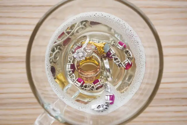 Biżuteria w szklanej misce z wodą i pianą.