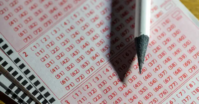 Zbliżenie na kupon lotto z zaznaczonymi liczbami i ołówkiem.