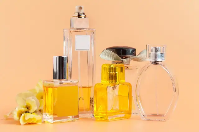 Kilka eleganckich flakonów z perfumami, w tym jeden z żółtym płynem i kwiatową ozdobą. Woda toaletowa ile ma procent? To zależy od jej stężenia.