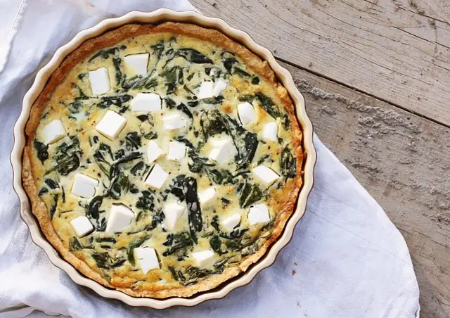 Pyszne ciasto na tartę wytrawną ze szpinakiem i fetą, gotowe do podania.
