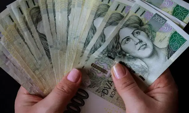 Dłonie trzymające stos banknotów 2000 koron czeskich. Czy to znak, które banki są zagrożone upadłością w Polsce?