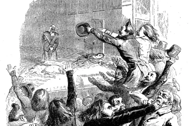 Tłum szaleje, wznosząc ręce i czapki. Na scenie leżą ciała, a postać w todze stoi z opuszczoną głową. To obraz pełen emocji, ukazujący cechy dramatu romantycznego.