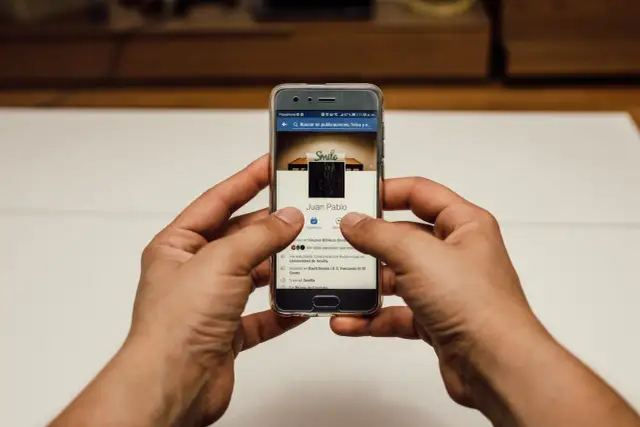 Ręce trzymające smartfon z profilem na Facebooku. Szukasz informacji, jak usunąć relacje na FB?