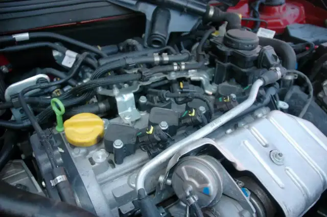 Widok na silnik samochodowy, gdzie są świece zapłonowe. Widać cewki zapłonowe, przewody i elementy układu dolotowego.