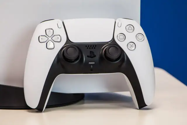 Biały kontroler DualSense od PS5 na jasnym tle.