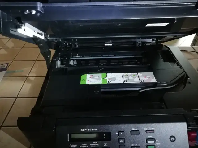 Otwarta drukarka Brother DCP-T510W z widocznymi instrukcjami i panelem sterowania.