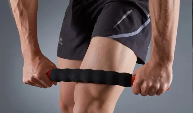 Mężczyzna masuje udo wałkiem do masażu.