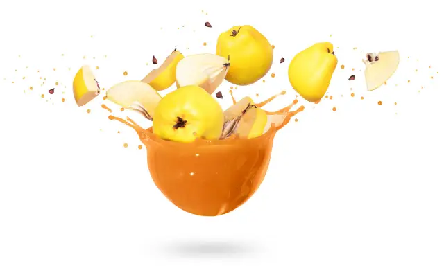 Rozbryzgujący się sok z pigwy w misce, z owocami i pestkami w powietrzu. Warto znać sok z pigwy przeciwwskazania.