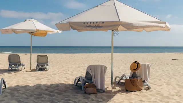 Leżaki i parasole na piaszczystej plaży nad morzem.