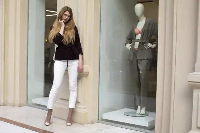 Modelka w białych spodniach i bordowym żakiecie obok manekina w szarym komplecie. Inspiracja skandynawskie marki odzieżowe.