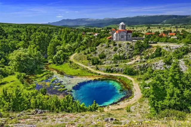 Niebieskie "oko ziemi" w Chorwacji, źródło rzeki z kościołem na wzgórzu w tle.