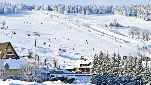 Stok narciarski w Karkonoszach, idealne miejsce na ferie zimowe 2026 dolnośląskie. Narciarze szusują po ośnieżonych zboczach, a kolejki linowe wwożą ich na szczyt.