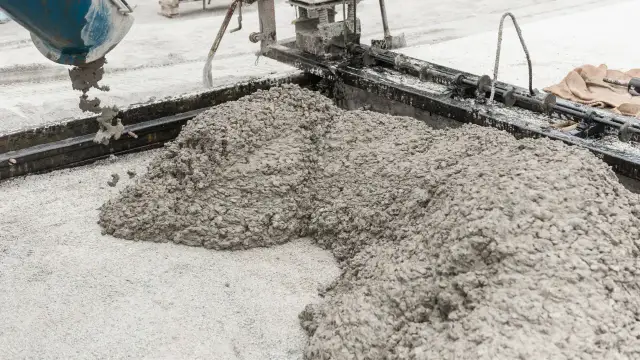 Świeża podsypka piaskowo cementowa wylewana z betoniarki na plac budowy.