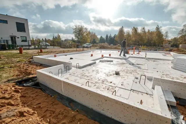 Budowa garażu murowanego: trwa wylewanie fundamentów z betonu i styropianu. Widać zbrojenie i elementy instalacji.