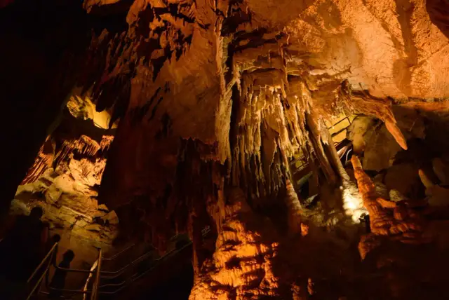 Wnętrze jaskini z naciekami, stalaktytami i stalagmitami, oświetlone ciepłym światłem. Możliwe, że to najdłuższa jaskinia na świecie.