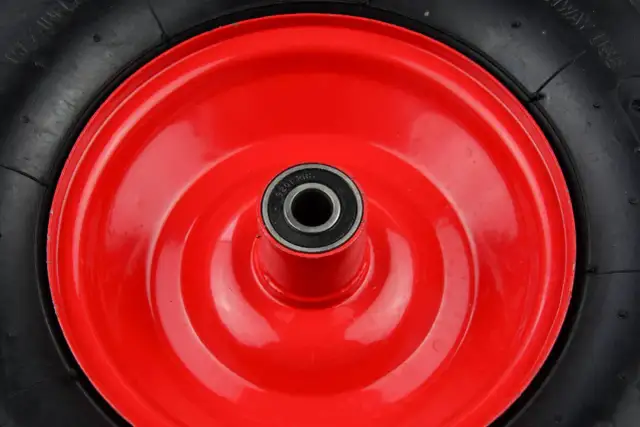 Czerwone koło taczki z czarną oponą i łożyskiem w środku.