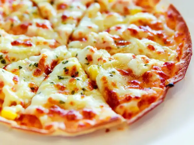 Zbliżenie na chrupiącą pizzę z roztopionym serem i ziołami.