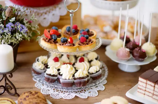 Stół z ciastkami, babeczkami, tartaletkami z owocami i cake pops.