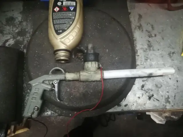 Domowy pistolet do malowania proszkowego z butelką płynu i elementami instalacji.