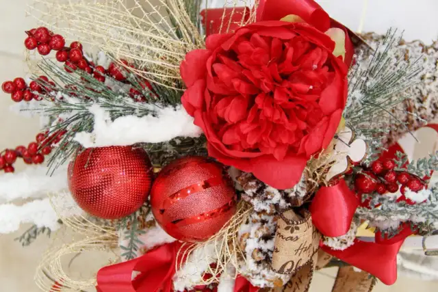 Czerwona, świąteczna kompozycja z bombkami, szyszkami i sztucznym śniegiem. Idealna inspiracja, jak ozdobić mieszkanie na święta.