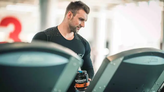 Mężczyzna z odżywką Supernova na bieżni, zastanawia się, czy robić cardio na masie.