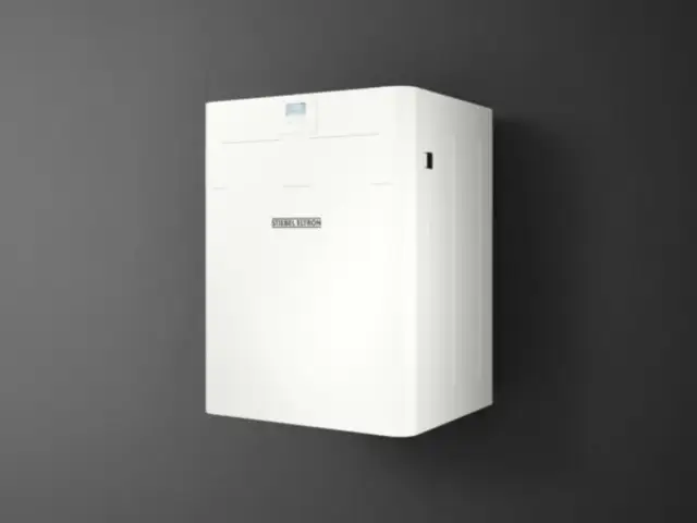 Biały, nowoczesny stiebel eltron rekuperator zamontowany na ciemnej ścianie. Urządzenie z dyskretnym wyświetlaczem i logo producenta.