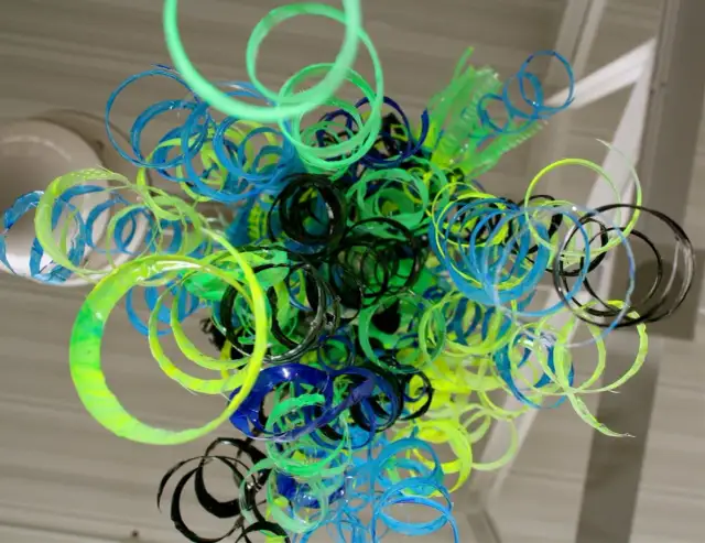 Kolorowa instalacja z upcyklingowanych plastikowych pierścieni w odcieniach zieleni, niebieskiego i czarnego.