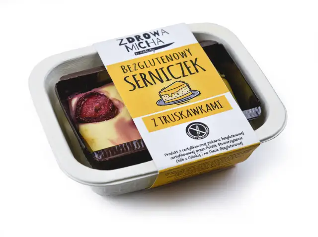 Bezglutenowy serniczek z truskawkami w białym opakowaniu.