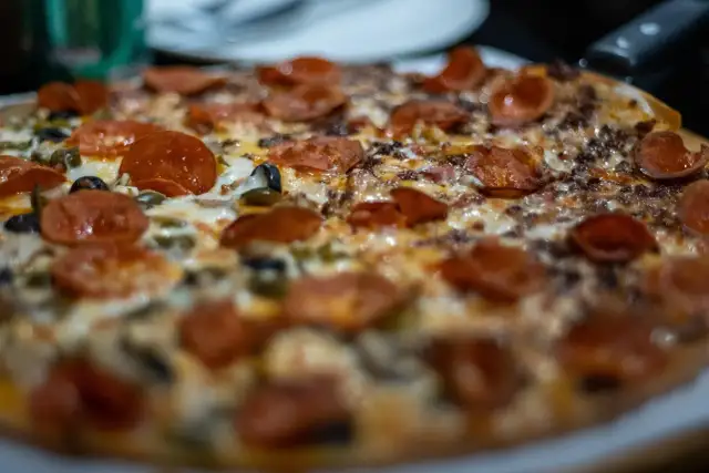 Pyszna pizza z pepperoni i oliwkami, idealna do pieczenia w wysokiej temperaturze.