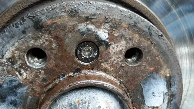 Rdza i zniszczenia na piaście koła, wskazujące na trudności w demontażu. Jak ściągnąć tarcze hamulcowe, gdy śruby są zapieczone?