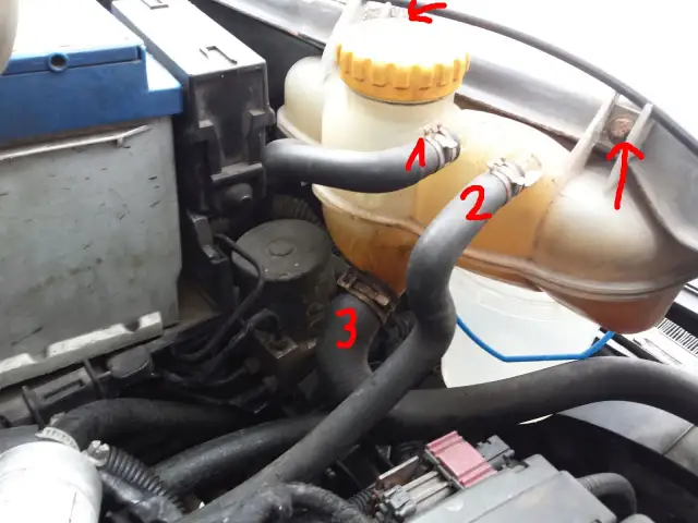 Zbiornik płynu chłodniczego w Oplu Meriva z zaznaczonymi wężami i strzałkami.