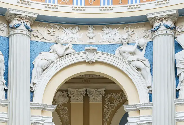 Barokowe stiuki: rzeźby kobiet, gryfy i ornamenty na tle błękitnej ściany.