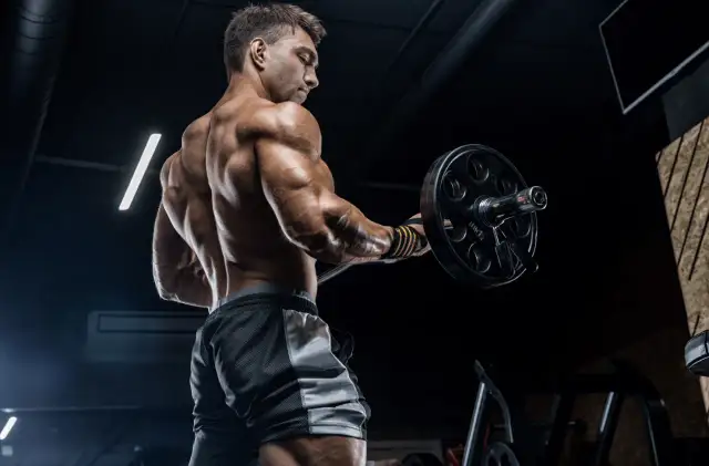 Mięśniowy mężczyzna wykonuje ćwiczenie z ciężarem. Zastanawia się, ile serii na trening będzie optymalne dla jego celów.