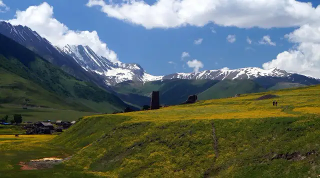 Górzysty krajobraz Gruzji z kwitnącymi polami i wieżami. Ceny w Gruzji są przystępne, a widoki zapierają dech.