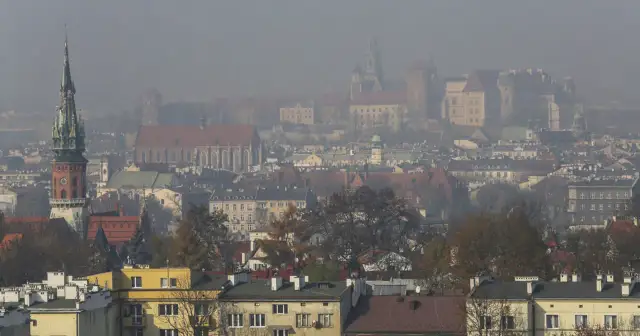 Mglisty widok Krakowa z wieżą kościelną i zamkiem. Warto wiedzieć, jak chronić się przed zanieczyszczeniami powietrza w takich warunkach.