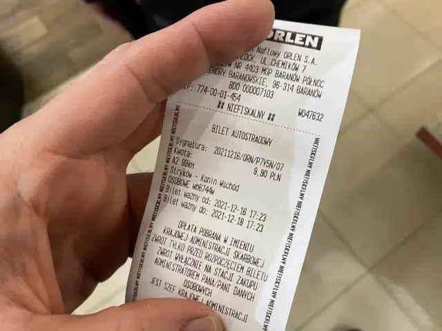 Dłoń trzyma paragon z biletem autostradowym ORLEN.