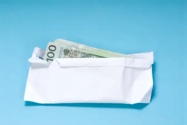Koperta z banknotami 100 zł. Zastanawiasz się, ile pieniędzy daje się na 18 urodziny?