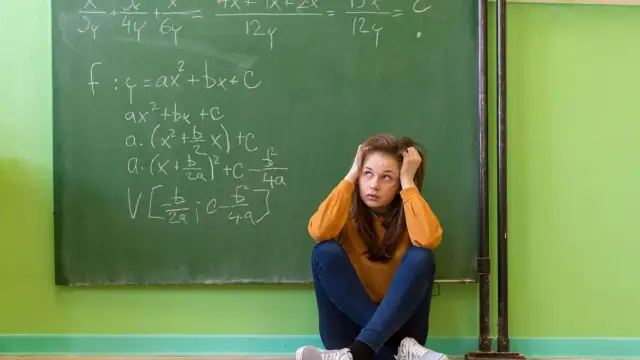 Dziewczyna zmagająca się z zadaniami matematycznymi na tablicy, symbolizująca dyskalkulię u dorosłych.